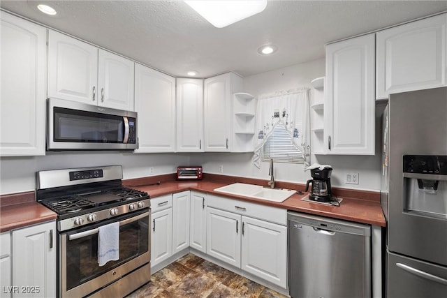 kitchen with white cabinetry, open shelves, a sink, and stainless steel appliances