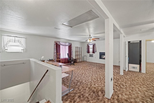 interior space featuring carpet flooring, attic access, ceiling fan, and a textured ceiling