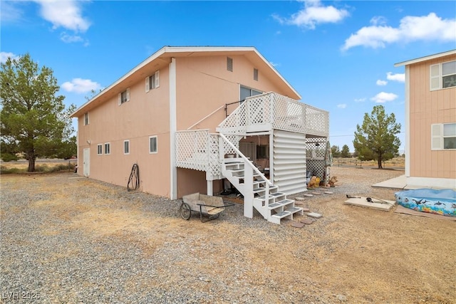 rear view of house featuring stairs and a wooden deck