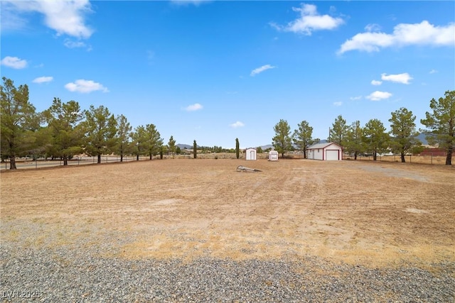 view of yard featuring an outbuilding, a rural view, and a detached garage