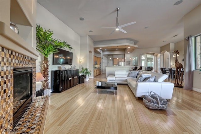 2064 Poetry Ave, Henderson, NV 89052 - living area featuring decorative columns, a ceiling fan, a brick fireplace, light wood-style flooring, and arched walkways