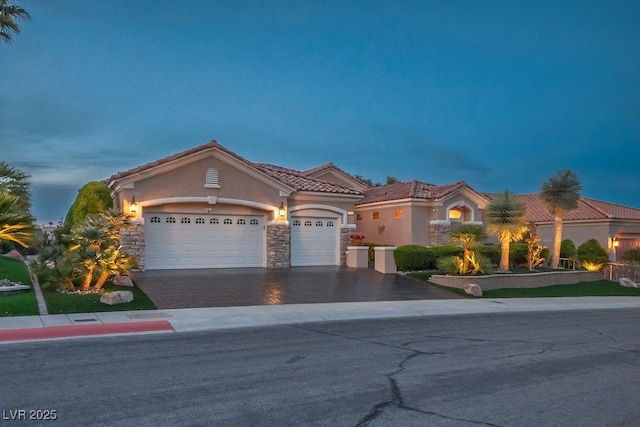 10524 Longwood Dr, Las Vegas, NV 89134 - mediterranean / spanish house featuring stone siding, driveway, a garage, a tile roof, and stucco siding