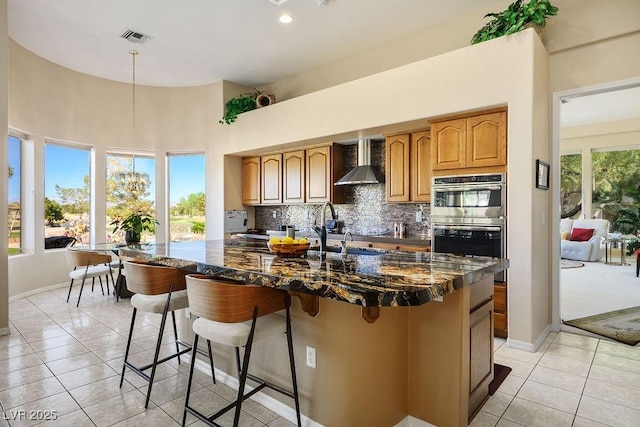 10524 Longwood Dr, Las Vegas, NV 89134 - kitchen featuring double oven, tasteful backsplash, dark stone countertops, wall chimney range hood, and visible vents
