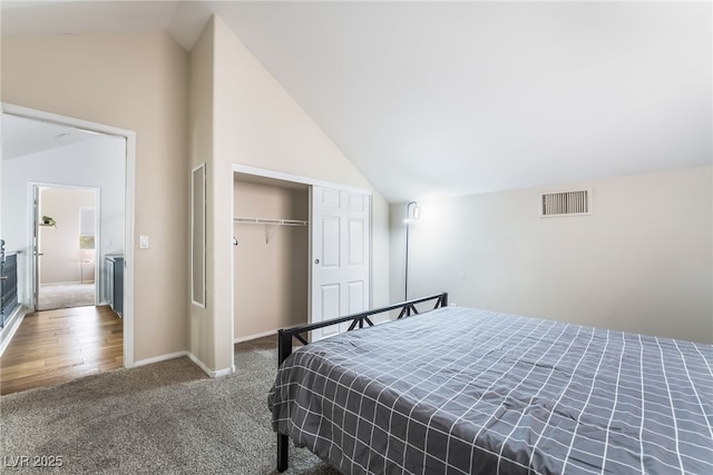 carpeted bedroom with baseboards, a closet, vaulted ceiling, and visible vents
