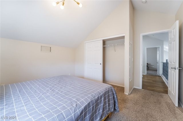 bedroom with lofted ceiling, carpet, baseboards, visible vents, and a closet