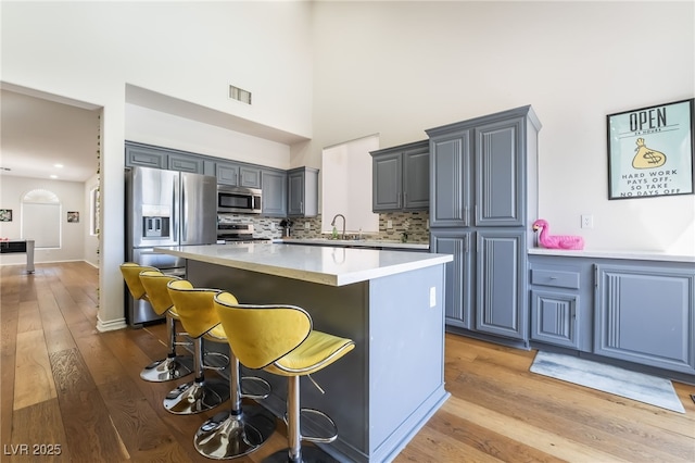 kitchen with gray cabinets, a sink, a kitchen island, appliances with stainless steel finishes, and visible vents