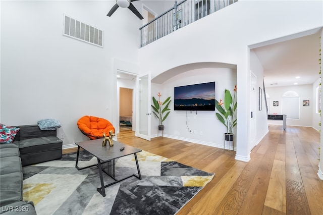 living area featuring baseboards, visible vents, ceiling fan, and wood-type flooring