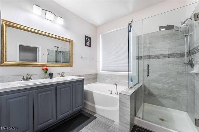 bathroom with a stall shower, double vanity, a sink, and a garden tub
