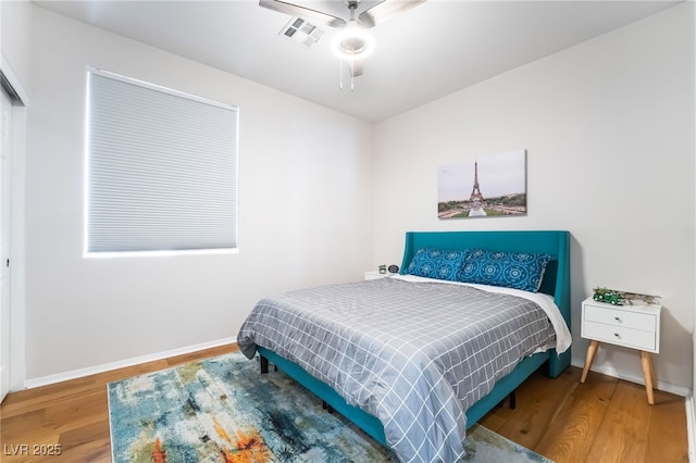 bedroom featuring baseboards, visible vents, wood finished floors, and a ceiling fan