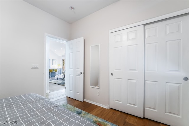 unfurnished bedroom with baseboards, a closet, and wood finished floors