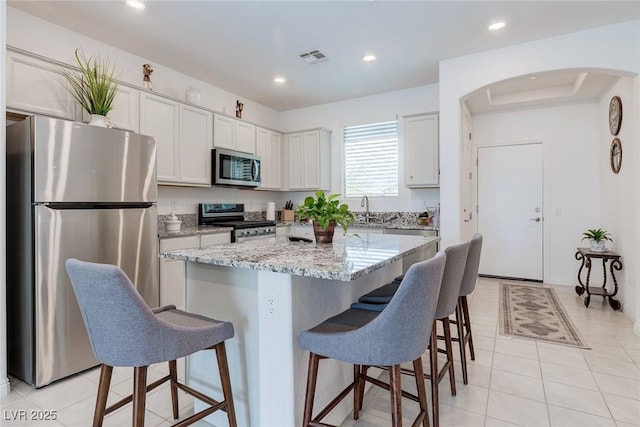 2114 Cold Canyon Ave, North Las Vegas, NV 89086 - kitchen with arched walkways, a kitchen bar, a center island, and appliances with stainless steel finishes