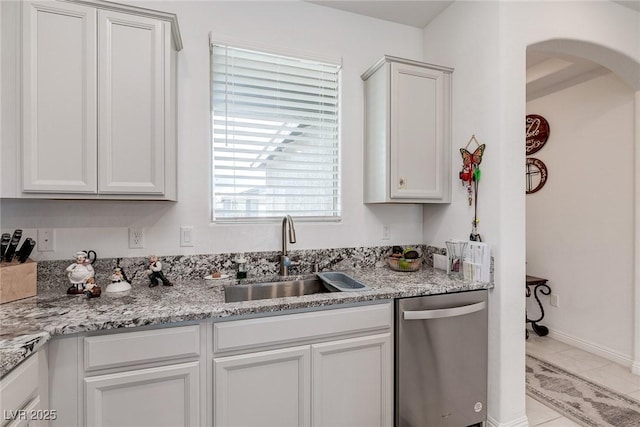 2114 Cold Canyon Ave, North Las Vegas, NV 89086 - kitchen featuring light stone counters, a sink, white cabinetry, stainless steel dishwasher, and arched walkways
