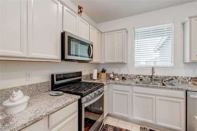 2114 Cold Canyon Ave, North Las Vegas, NV 89086 - kitchen featuring light tile patterned floors, stainless steel appliances, a sink, light stone counters, and white cabinets