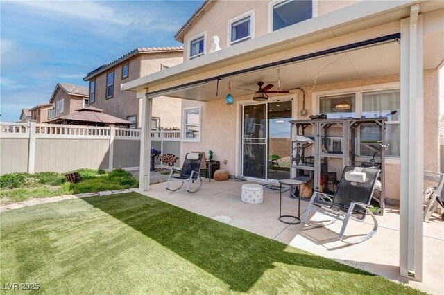 rear view of house with stucco siding, fence, a yard, and a patio area