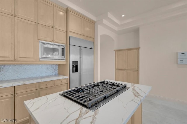 2290 Casa Bella Ct, Las Vegas, NV 89117 - kitchen with built in appliances, a center island, light brown cabinetry, tasteful backsplash, and light stone counters