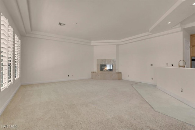 2290 Casa Bella Ct, Las Vegas, NV 89117 - unfurnished living room featuring a tray ceiling, light colored carpet, a tiled fireplace, and recessed lighting