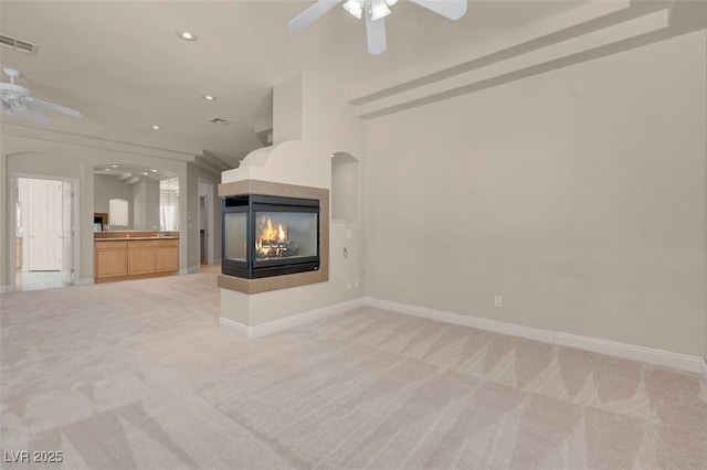 2290 Casa Bella Ct, Las Vegas, NV 89117 - unfurnished living room featuring ceiling fan, light colored carpet, recessed lighting, a multi sided fireplace, and arched walkways
