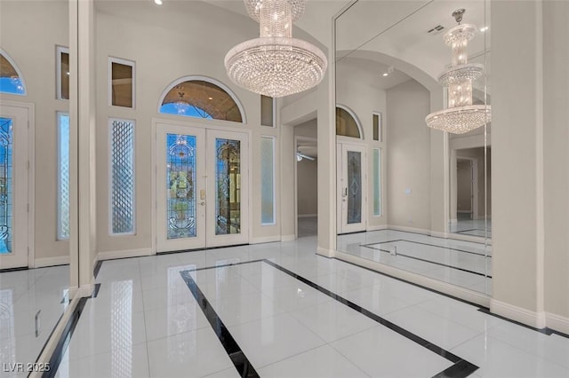 2290 Casa Bella Ct, Las Vegas, NV 89117 - foyer entrance with french doors, a chandelier, inlaid floor details, a towering ceiling, and arched walkways