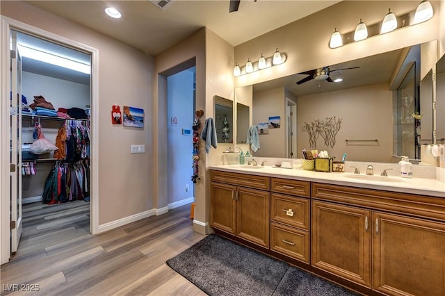 9511 Star Vista Ct, Las Vegas, NV 89149 - bathroom featuring wood finished floors, a ceiling fan, double vanity, a walk in closet, and baseboards