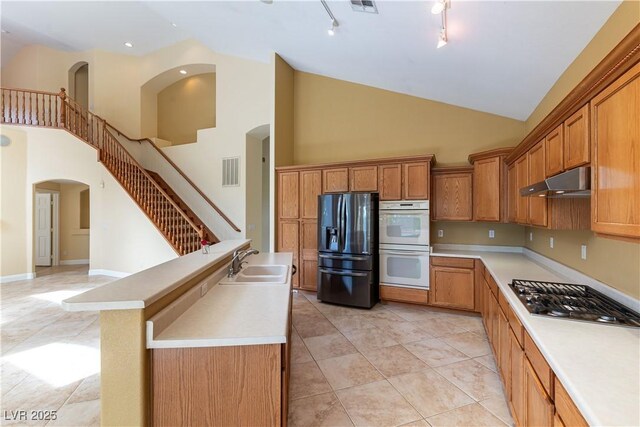 812 Eaglewood Dr, Las Vegas, NV 89144 - kitchen with black fridge, stainless steel gas cooktop, double oven, high vaulted ceiling, and under cabinet range hood