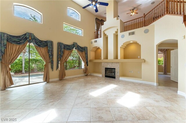 812 Eaglewood Dr, Las Vegas, NV 89144 - unfurnished living room featuring ceiling fan, a towering ceiling, a tile fireplace, built in shelves, and arched walkways