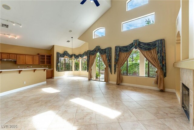 812 Eaglewood Dr, Las Vegas, NV 89144 - unfurnished living room featuring rail lighting, a high ceiling, ceiling fan, and a tile fireplace