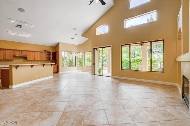 812 Eaglewood Dr, Las Vegas, NV 89144 - unfurnished living room with ceiling fan, a high ceiling, rail lighting, light tile patterned floors, and a tile fireplace