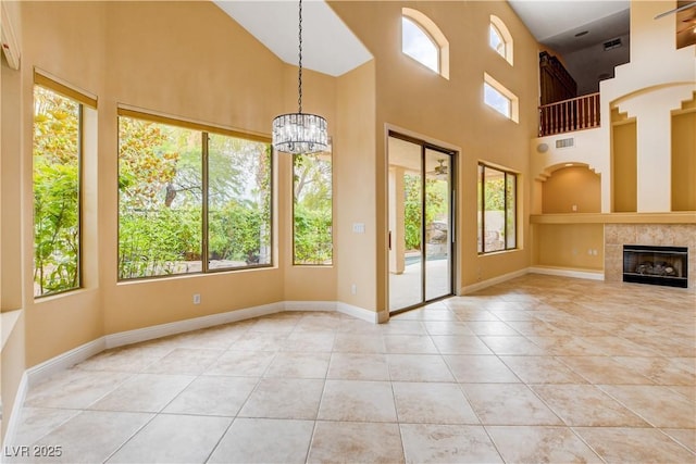 812 Eaglewood Dr, Las Vegas, NV 89144 - unfurnished living room featuring tile patterned flooring, a high ceiling, a chandelier, and a tile fireplace