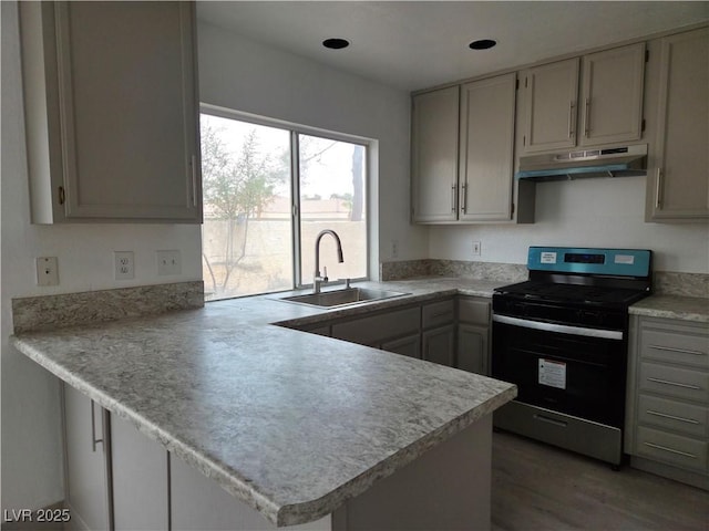 kitchen featuring a sink, light countertops, stainless steel electric stove, a peninsula, and under cabinet range hood
