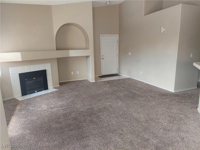 unfurnished living room with baseboards, carpet, and a tile fireplace