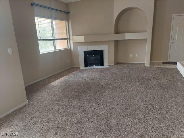 unfurnished living room with baseboards, carpet, and a tile fireplace