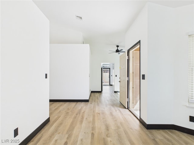hallway featuring baseboards, visible vents, and light wood finished floors