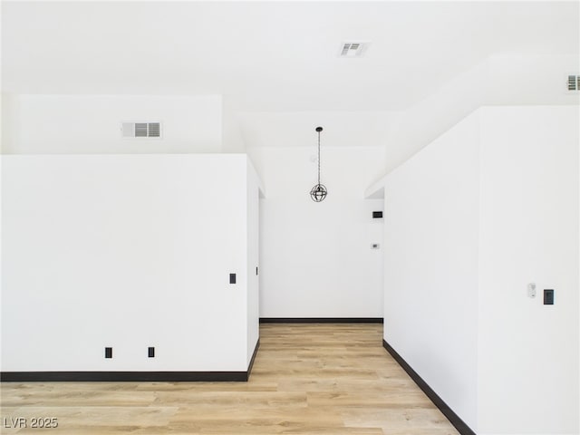 spare room featuring baseboards, light wood-type flooring, and visible vents