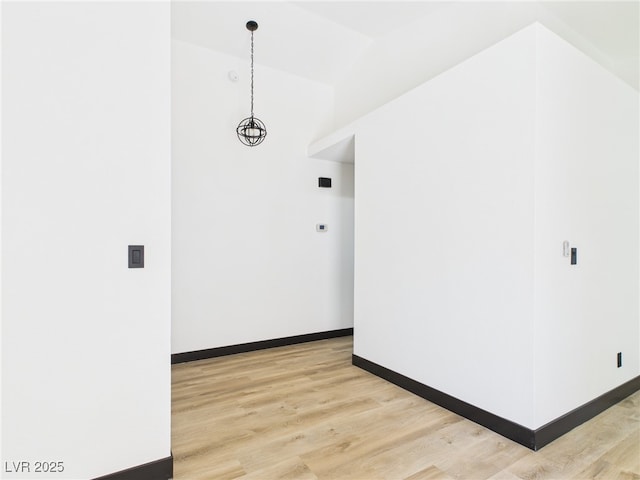 empty room featuring baseboards, light wood-style flooring, and lofted ceiling