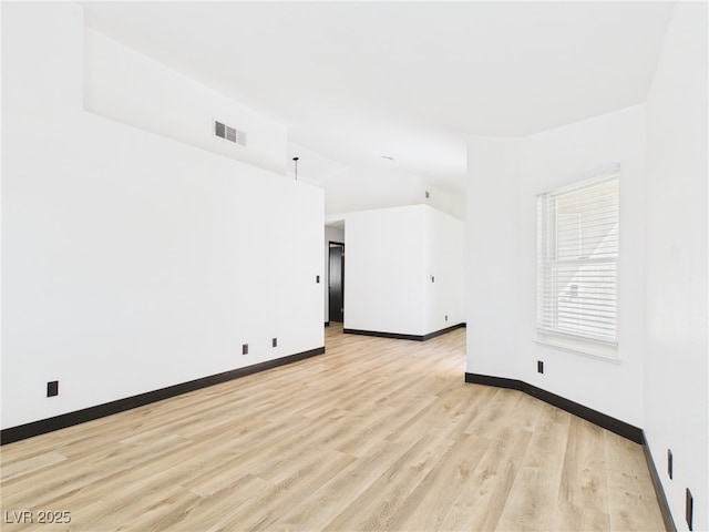 unfurnished room featuring baseboards, visible vents, vaulted ceiling, and light wood-style floors