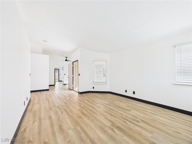 unfurnished living room with ceiling fan, plenty of natural light, light wood-style flooring, baseboards, and lofted ceiling