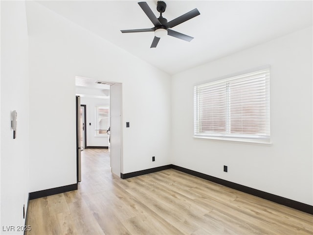 spare room with a ceiling fan, visible vents, baseboards, lofted ceiling, and light wood-style flooring