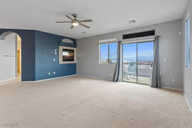 640 Finch Island Ave, Henderson, NV 89015 - carpeted empty room featuring ceiling fan, arched walkways, a glass covered fireplace, baseboards, and visible vents