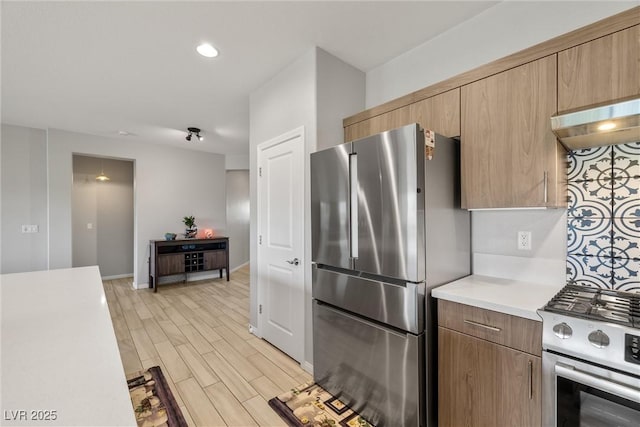 kitchen featuring light wood-type flooring, baseboards, appliances with stainless steel finishes, and light countertops
