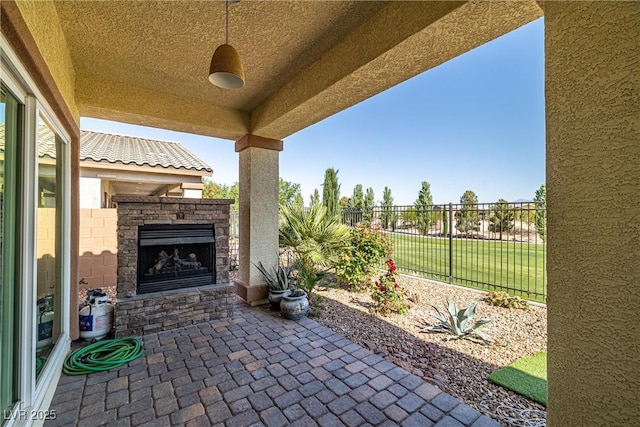 view of patio featuring an outdoor stone fireplace and fence