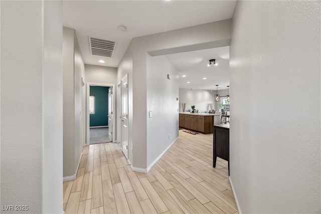 hall with light wood finished floors, recessed lighting, visible vents, and baseboards