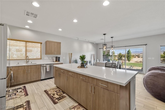 kitchen featuring appliances with stainless steel finishes, visible vents, light countertops, and a sink
