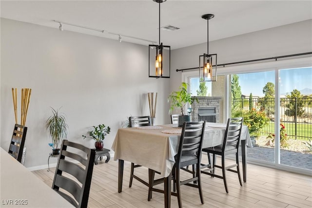dining room featuring track lighting, visible vents, a fireplace, and light wood-style flooring