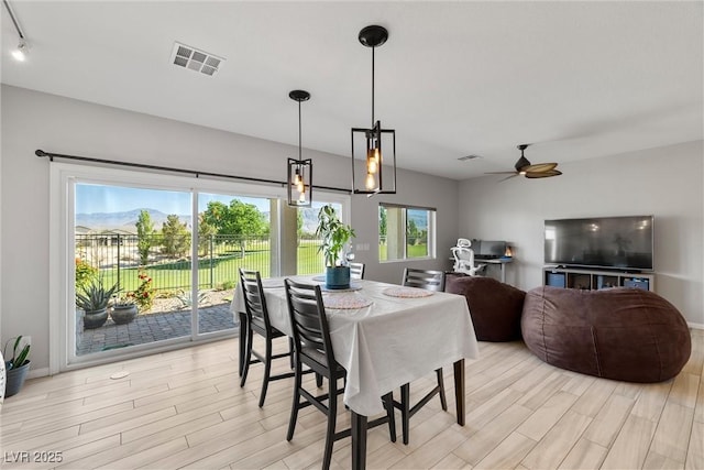 dining area with light wood finished floors, visible vents, ceiling fan, and baseboards