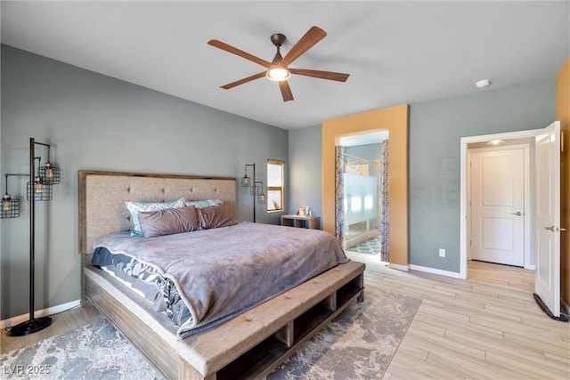 bedroom with light wood-type flooring, ensuite bathroom, a ceiling fan, and baseboards