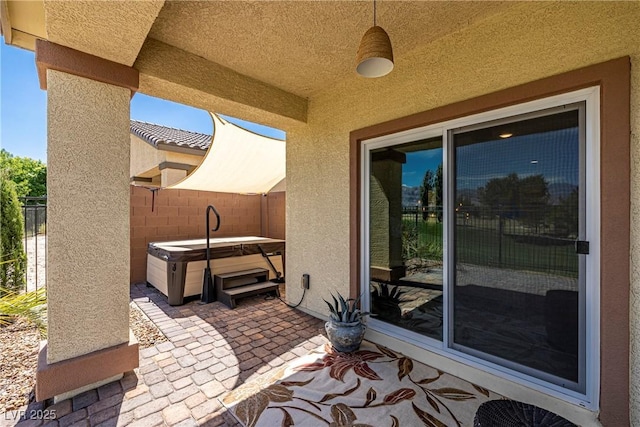 view of patio featuring fence and a hot tub