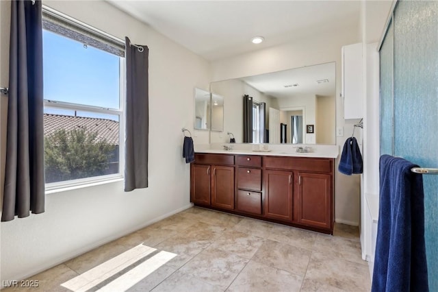 full bathroom with a sink, double vanity, baseboards, and a healthy amount of sunlight