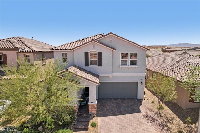 view of front facade with an attached garage, decorative driveway, stucco siding, and a tiled roof