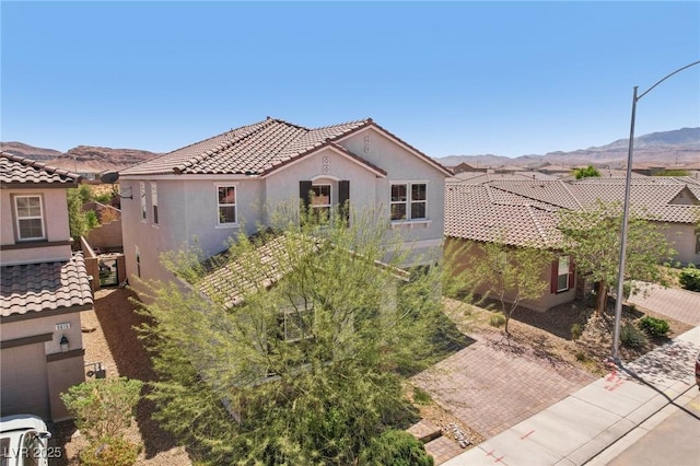 view of front facade with a mountain view, stucco siding, and a tiled roof