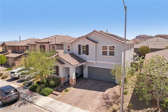view of front of house featuring stucco siding, decorative driveway, an attached garage, and a tile roof